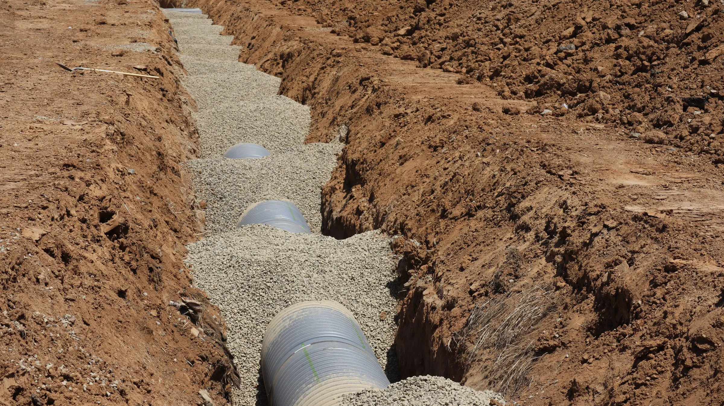 Perforated drain pipe laid in a gravel-lined trench
