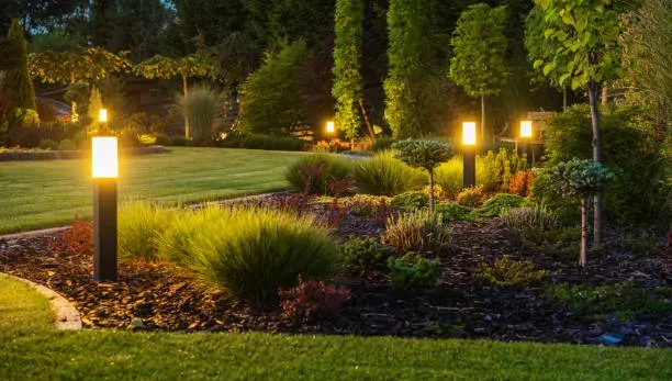 Low-voltage path lights glowing along a landscaped bed at dusk