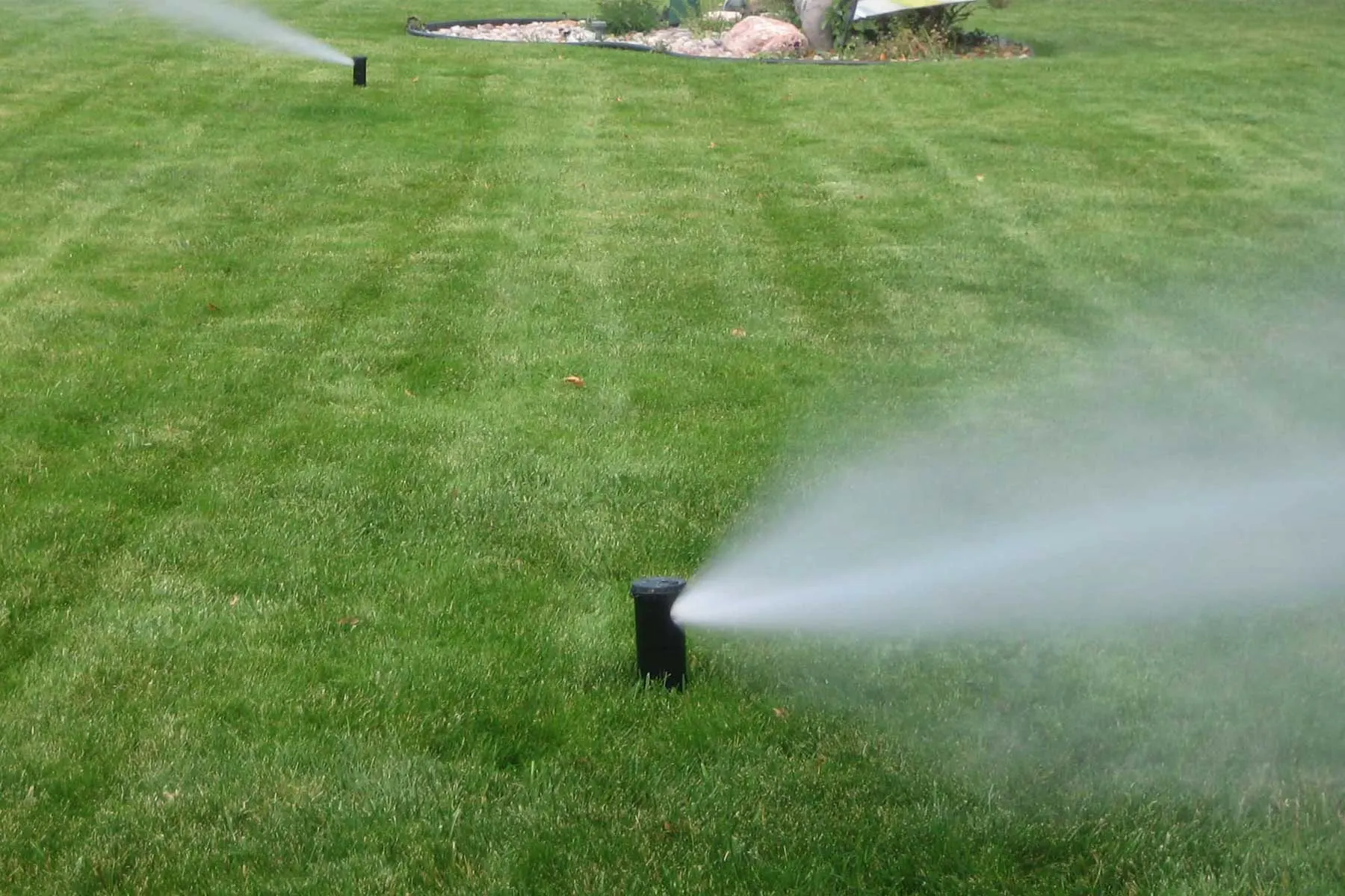 Pop-up sprinkler heads releasing air and mist during a system blowout